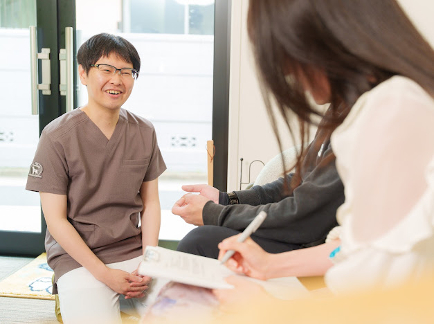 明るい院内で、施術者がご夫婦と対話している様子。